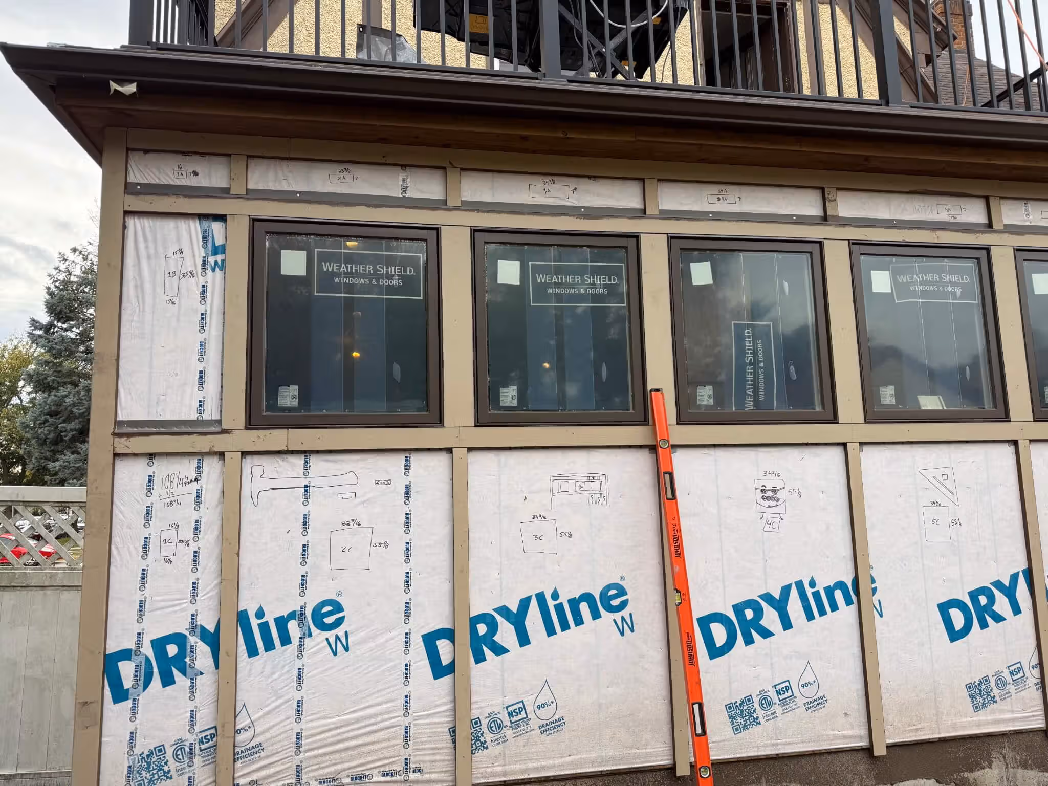 Construction of exterior wall with four Weather Shield windows installed and DRYline house wrap applied.